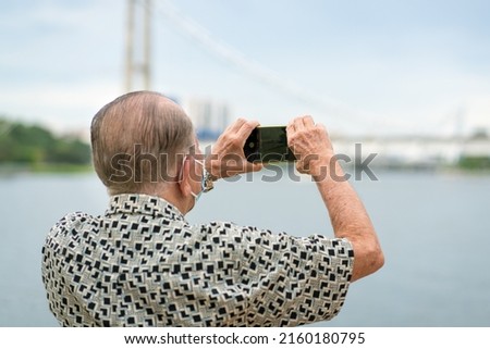 Senior man using smartphone to take photos and video. Travel and technology lifestyle for seniors.