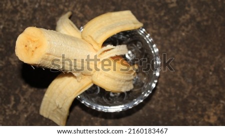 Peeled banana slices in transparent glass cup bowl on concrete background with copy space. Healthy natural vitamin snacks. Top view, yellow group fruit for vegetarian, sweet tropical dessert.