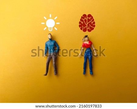 Women and man miniature people with the idea and brain icons on a yellow background.