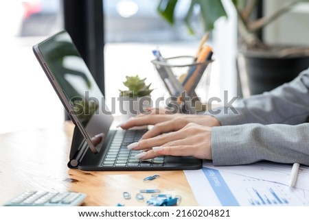 Close-up of professional young woman manager using tablet at her office, Hands of a young woman typing on the keypad of a tablet. Royalty-Free Stock Photo #2160204821