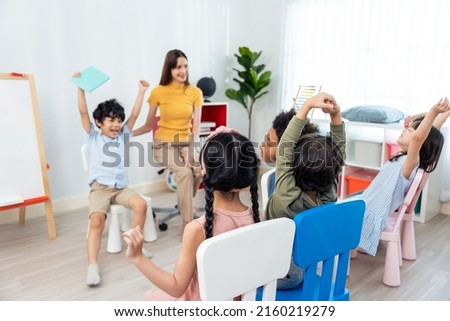 Asian beautiful young woman teacher teaching mixed race kids at school. Attractive Instructor master female explain and educate reading book with child student kindergarten pre school in classroom. Royalty-Free Stock Photo #2160219279