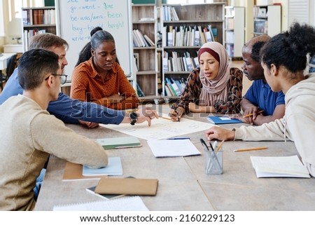 Group of multi-ethnic immigrant students attending international school lessons working on English language poster together Royalty-Free Stock Photo #2160229123
