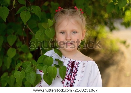 Portrait of a smiling girl with a flower in a Ukrainian embroidered shirt. Red berries of viburnum in the hair. Ukrainian culture and traditions.