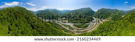 Panorama view: Cable-Stayed Bridge on the Adler-Krasnaya Polyana motorway. Aerial view of car driving along the winding mountain road in Sochi, Russia. Royalty-Free Stock Photo #2160234469