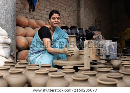 Skilled hands of a female potter shaping the clay into pot on spinning wheel Royalty-Free Stock Photo #2160235079