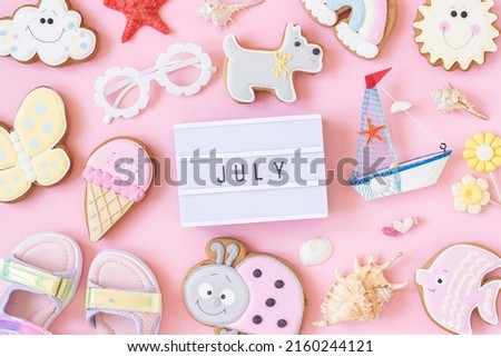 July text on lightbox and cute summer symbols on pink background. Top view, Flat lay. Creative summer concept, greeting card.