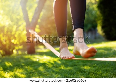 woman walking on a slackline in a park at sunset. core balance training Royalty-Free Stock Photo #2160250609