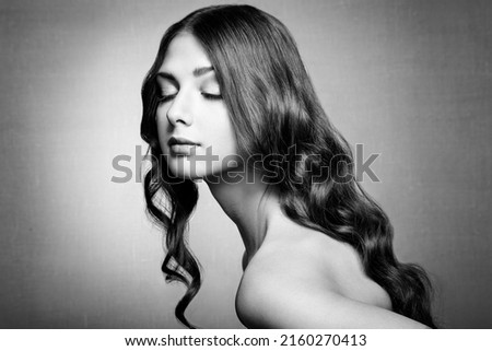 Brunette Girl with Long Healthy and Shiny Curly Hair. Care and Beauty. Beautiful Model Woman with Wavy Hairstyle. Black and White photo