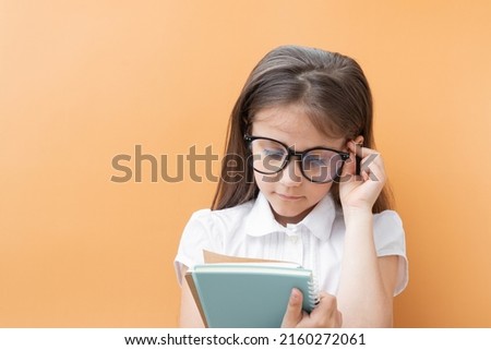 A 7-year-old girl in glasses with notebooks. Children's education, learning concept.