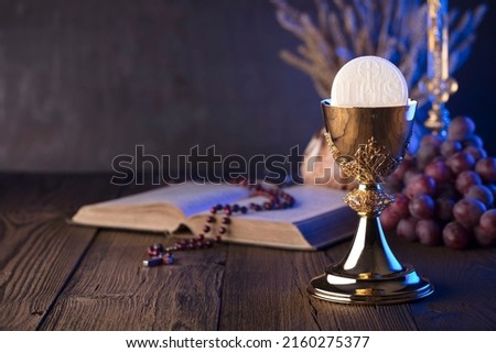 Golden chalice and opened bible on rustic wooden table. Royalty-Free Stock Photo #2160275377