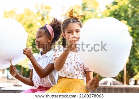 Cute little girls with cotton candy outdoors Royalty-Free Stock Photo #2160278063