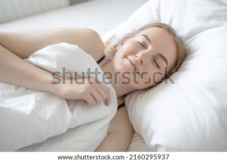 Beautiful young blonde hair woman sleeping, enjoying bed time in the morning keeping eyes in bed. 