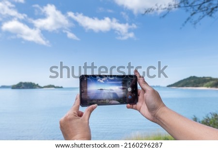 Taking photo on mobile phone of sea view, take Photo Vacation time to the Sea, Hand on Mobile take Sea scape view.  