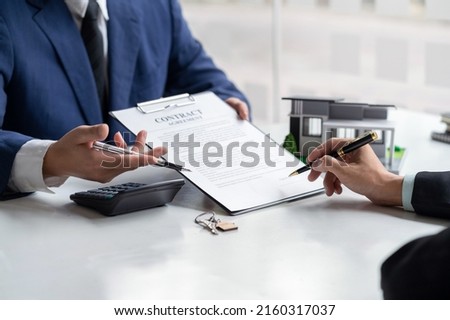 Signing a home loan purchase agreement with a real estate agent.