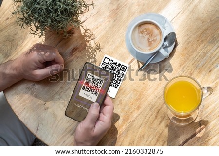 A customer scanning a qr code with his cell phone in a bar or restaurant to read the menu. The hospitality industry and new technologies Royalty-Free Stock Photo #2160332875