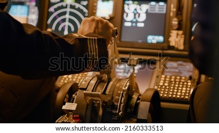 Aircraft captain in cockpit command taking off with airplane, throttling power engine lever to navigate radar compass. Airline service to fly plane with dashboard and control panel. Close up. Royalty-Free Stock Photo #2160333513