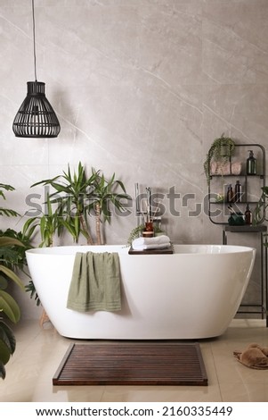 Modern white tub and beautiful green houseplants in bathroom. Interior design Royalty-Free Stock Photo #2160335449