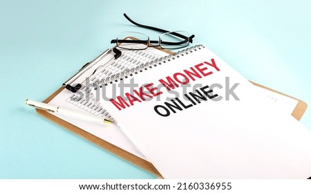 MAKE MONEY ONLINE text on notepad on clipboard with chart on a blue background, concept closeup. Business and finance concept