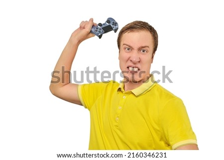 Angry gamer with wireless gamepad dressed in yellow T-shirt isolated on white background. Furious man throwing game joystick in TV, loss in video game concept, video game addiction