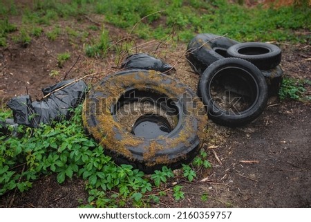 Illegal dumping of tyres in the countryside. The concept of environmental pollution. Royalty-Free Stock Photo #2160359757