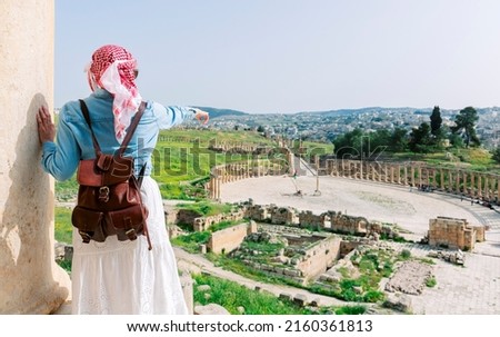 Jerash - jordan. travel tourism holiday background -young girl with hat standing pointing to Ancient Roman city of Gerasa of Antiquity, Jerash Royalty-Free Stock Photo #2160361813