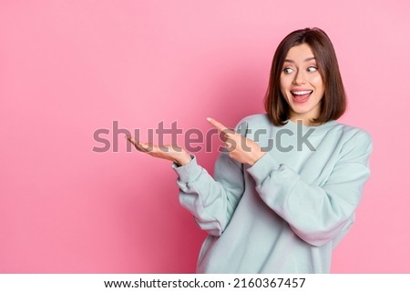 Photo of hooray young lady look hold empty space wear blue hoodie isolated on pink color background