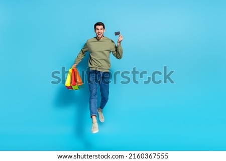 Full length photo of active energetic guy hold debit card mall packages isolated on blue color background
