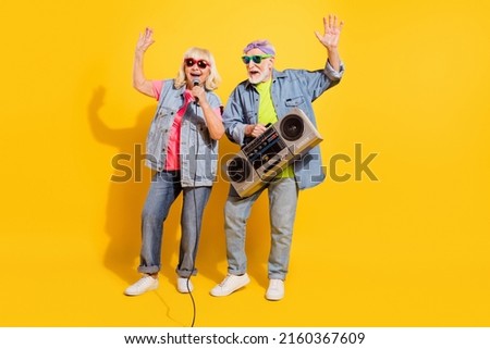 Photo of excited pretty husband wife wear jeans shirts singing listening boombox isolated yellow color background