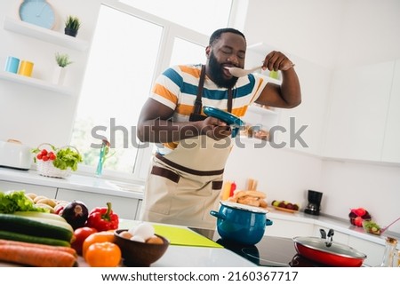 Photo of young cheerful guy good mood cooking dinner taste yummy fresh soup cuisine culinary indoors Royalty-Free Stock Photo #2160367717