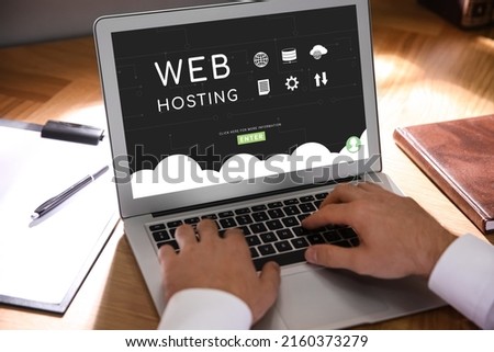 Web hosting service. Man working with modern laptop at wooden table