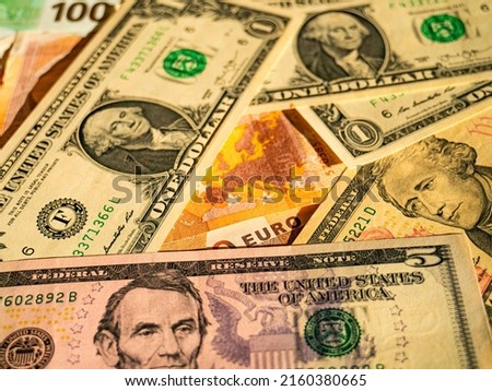 Strong dollar - weak euro. Euro banknotes under dollars. Europe's dependence on the USA .Concept photo of weakness of the European economy, eurozone,inflation, strong USA economy, strong dollar.
