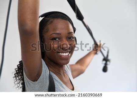 African American Woman Smiling Working on Movie Set as Audio Person Holding Boom Pole Microphone. She is a Video Production Crew Member
