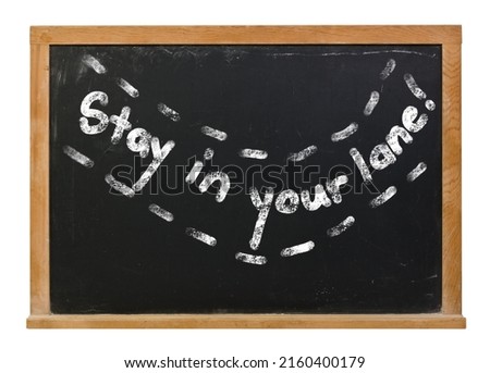 Stay in your lane written in white chalk on a black chalkboard isolated on white Royalty-Free Stock Photo #2160400179
