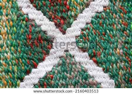 Close-up of a knitted fabric made of thick threads with wool. Background with knitted cross.
