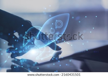 Successful business and startup concept with double exposure of human finger on digital tablet screen and virtual blue light rocket