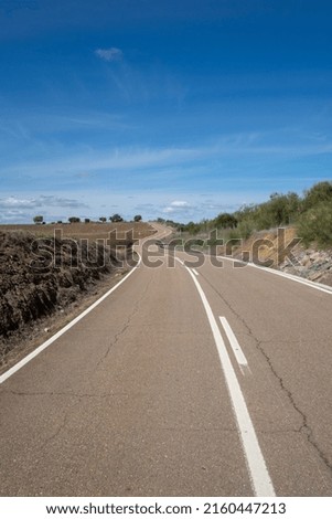 curvy asphalt road to the hill with blue sky along the sanatiago path