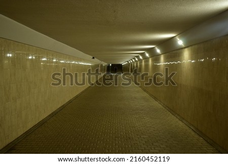 Underpass with electric lighting and reflection of light from walls with ceramic tiles