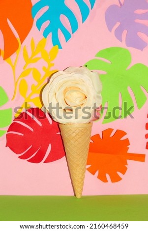 ice cream cone with white flower head in it on pink green background with tropical leaves, summer design, vocation, romance