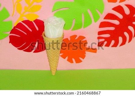 ice cream cone with white flower head in it on pink green background with tropical leaves, holiday time, rechargeable batteries