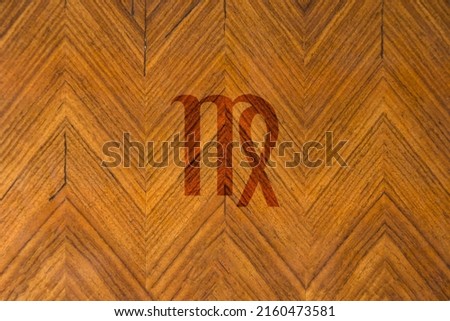Close-up shot of a wooden surface engraved with a zodiac sign, especially the sign of Virgo
