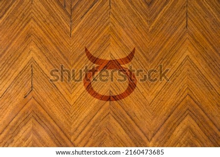Close-up shot of a wooden surface engraved with a zodiac sign, especially the sign of Taurus
