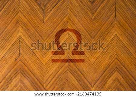 Close-up shot of a wooden surface engraved with a zodiac sign, especially the sign of Libra