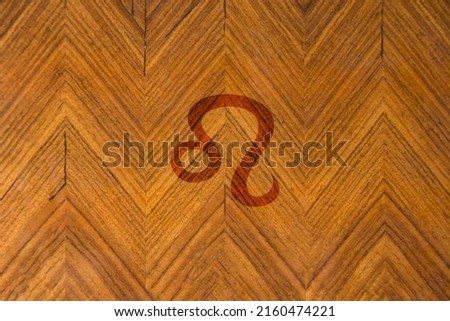 Close-up shot of a wooden surface engraved with a zodiac sign, especially the sign of Leo