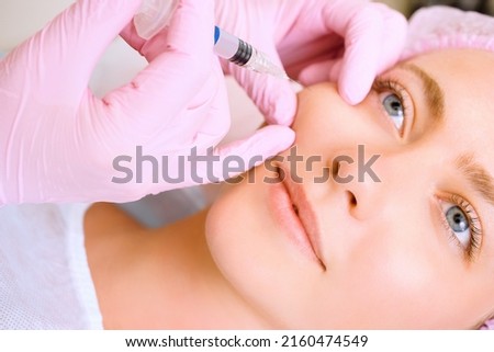 Image of a young beautiful woman dressed as a patient, lying on a couch in a cosmetology clinic. Royalty-Free Stock Photo #2160474549