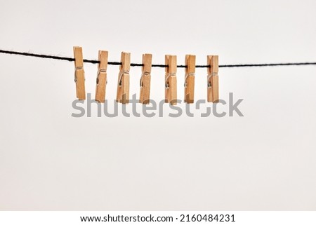 Miniature wooden clothespins hanging on shurka on a white background. Royalty-Free Stock Photo #2160484231