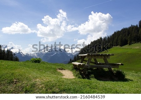 Mountain peak panoramic view on green grass alpine valley with wooden table and bench Savoie Mont Blanc  region France