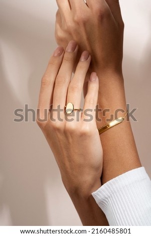 Woman Jewelery concept. Woman’s hands close up wearing rings and bracelet modern accessories elegant life style. Beige background  Royalty-Free Stock Photo #2160485801