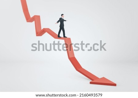 Crisis management concept with businessman keeping balance trying to stay afloat on red arrow down on abstract light background