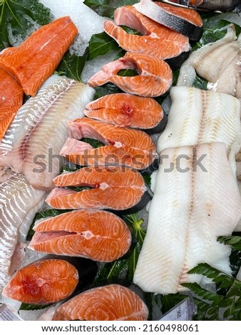 fresh seafood is laid out on the counter. fresh salmon trout steak, cod fillet, halibut fillet. healthy food for heart