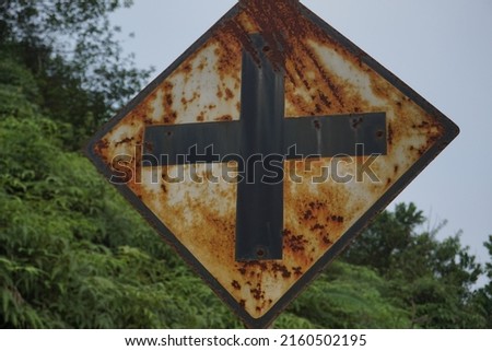 is an old and rusty four-crossing sign, a black and white sign
